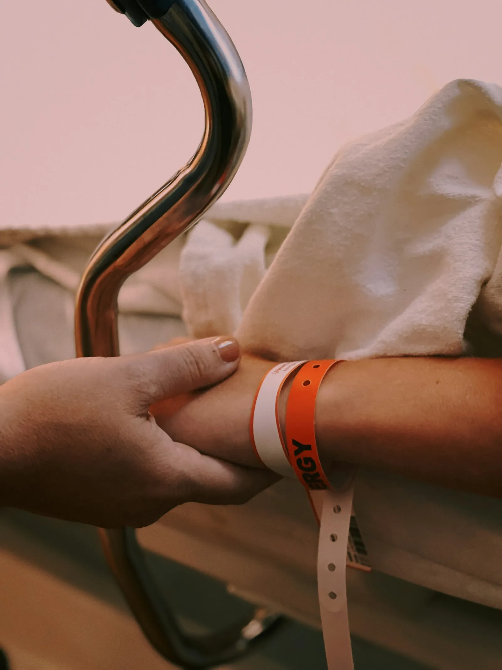 A patient's wrist with hospital identity bands, held by another hand